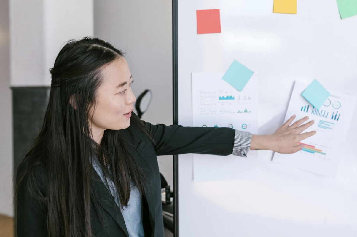 Asian Woman Holding Notes Against a Whiteboard